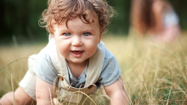 The little baby or year-old child on the grass in sunny summer day. The concept children's months, happy child playing