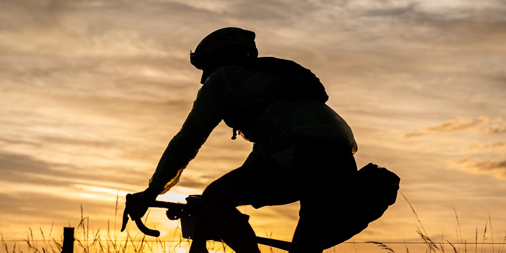 Cycliste en ombre chinoise sur la route au crépuscule lors de la cyclo Les Copains à Ambert 2022.