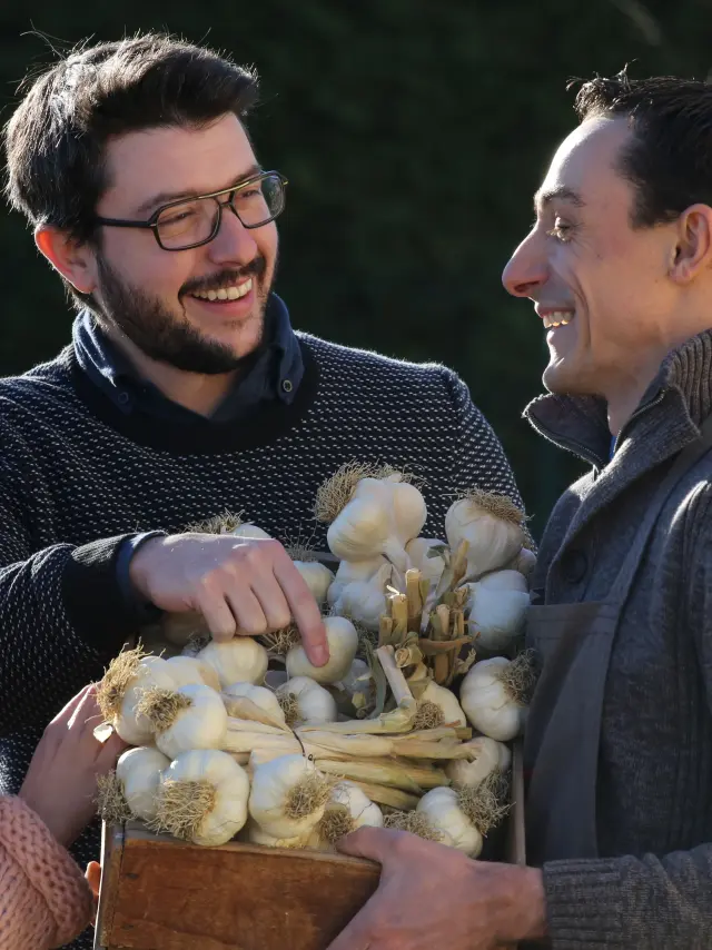 Couple discutant avec un producteur d’ail rose de Billom devant une caisse en bois.