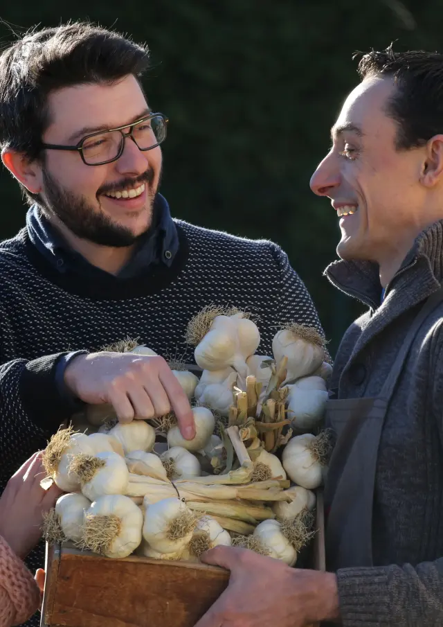 Couple discutant avec un producteur d’ail rose de Billom devant une caisse en bois.