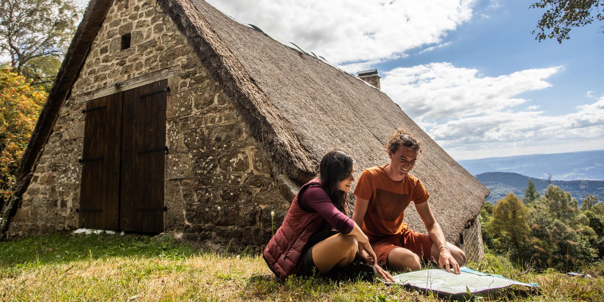 Couple devant une jasserie sur les Hautes Chaumes, consultant une carte.