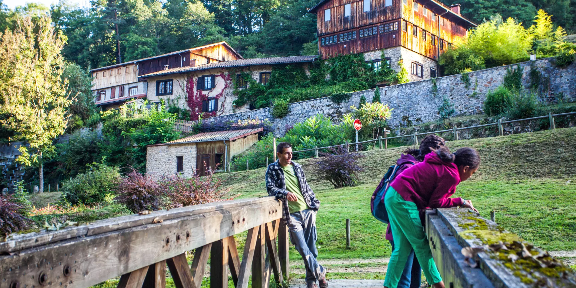 Famille sur un pont devant le Moulin Richard de Bas, entouré de nature.