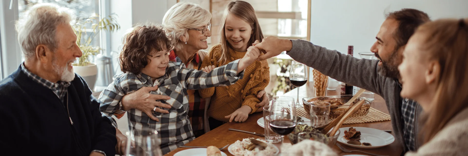 Illustration d’un repas de Noël en famille avec une grand-mère souriante entourée d’enfants, un grand-père et des parents autour d’une table festive en bois.