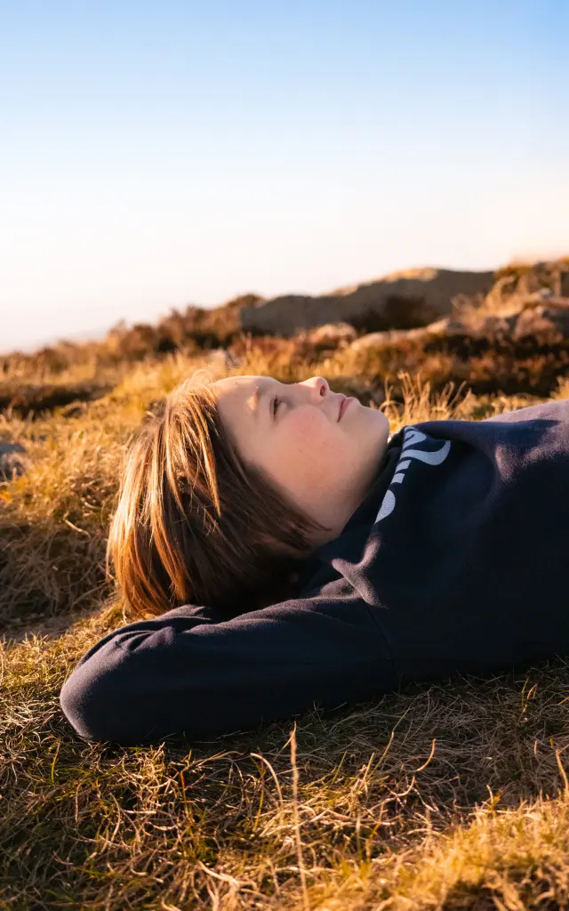 peyre mayou, pgoto d'une enfant allongé dans l'herbe en Livradois-Forez, Auvergne