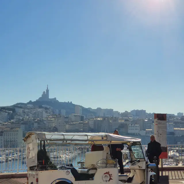 Tuk tuk à l'arrêt, en arrière plan le Vieux-Port et Notre-Dame de la Garde