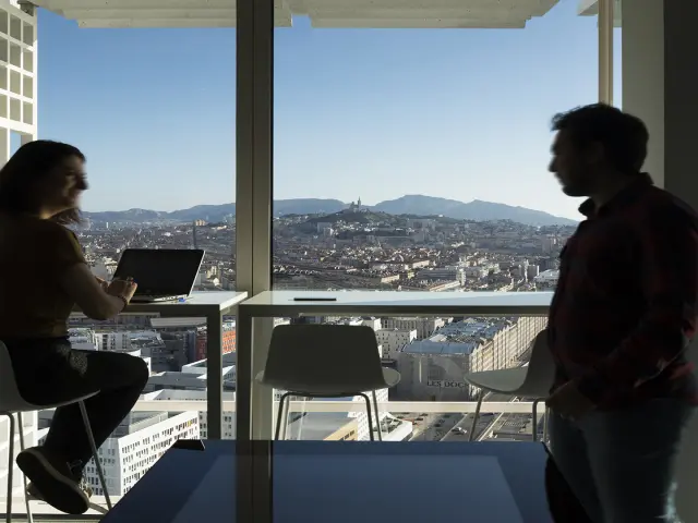 Tour La Marseillaise, personne travaillant dans un étage élevé avec en fond Notre-Dame de la Garde