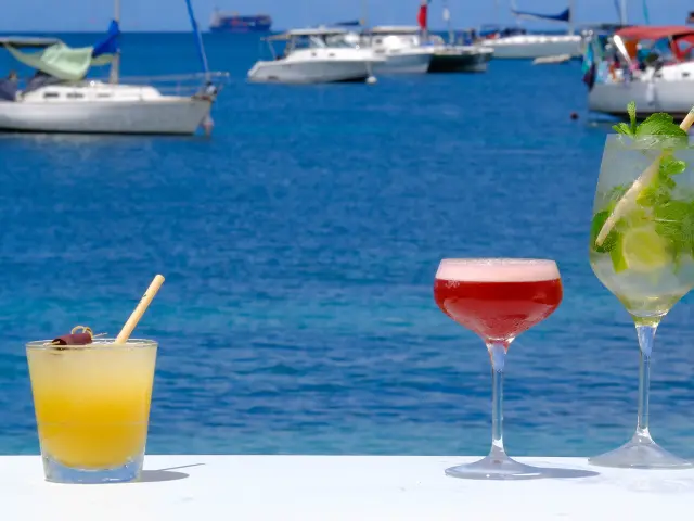 Cocktail servi sur une table du bar-lounge Le Kano, les pieds dans le sable face à la mer turquoise de l’Anse Mitan Martinique