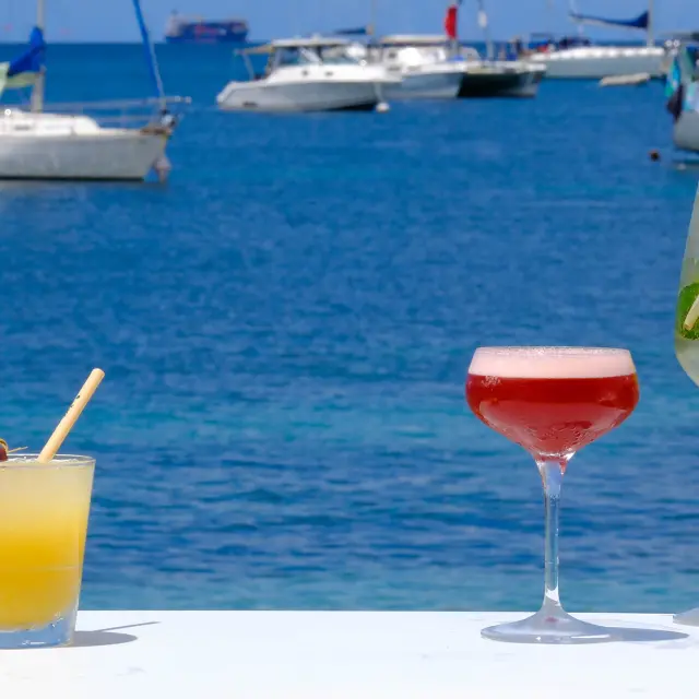 Cocktail servi sur une table du bar-lounge Le Kano, les pieds dans le sable face à la mer turquoise de l’Anse Mitan Martinique