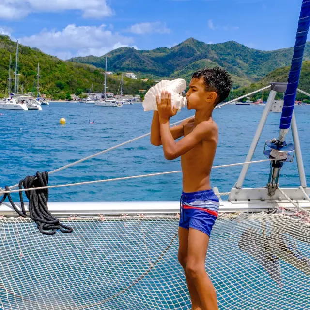 Souffler dans une conque de lambi Catamaran Kokoumdo Trois-Ilets Martinique