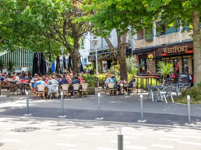 Des clients attablés en terrasse sous les arbres face aux bars d'une place du centre ville de Lorient