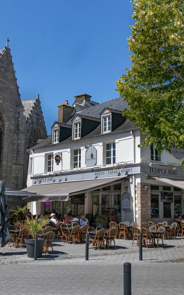 Terrasse ensoleillée du restaurant Temple Bar à côté de l'église en pierre de Ploermel