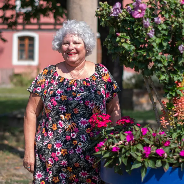 Une dame se tenant debout à côté d'un pot de fleurs