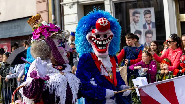 Verkleidete Menschen beim Karneval in Mulhouse während der Parade. Die Menschen tragen Masken und die Menge wirft Konfetti.