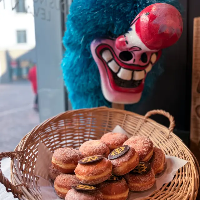 Un panier de boules de Berlin avec en arrière plan un masque de carnaval typique de la région mulhousienne