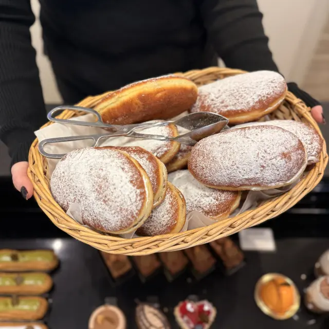 Un personne dont on ne voit pas le visage présente des beignets dans un panier