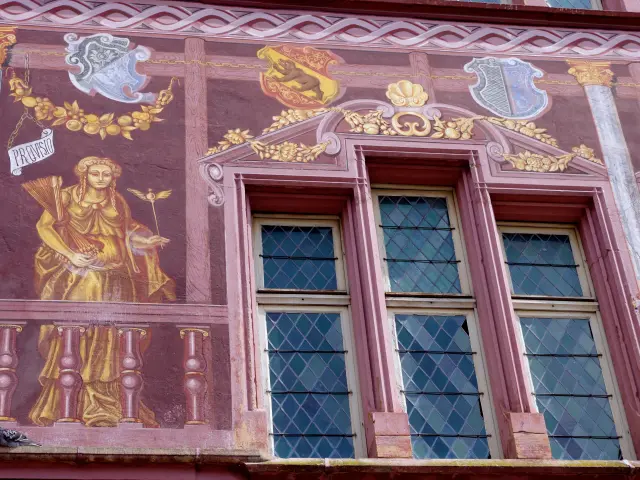 A wall of the former Mulhouse Town Hall, on which the coats of arms of certain Swiss cantons, an allegorical figure and an old window can be seen.