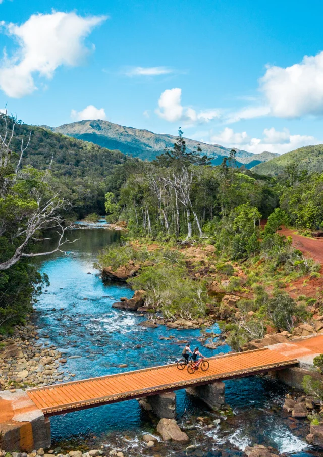 Traversée d'un pont en VTT au Parc Provincial de la Rivière Bleue à Yaté, dans le Grand Sud de la Nouvelle-Calédonie.