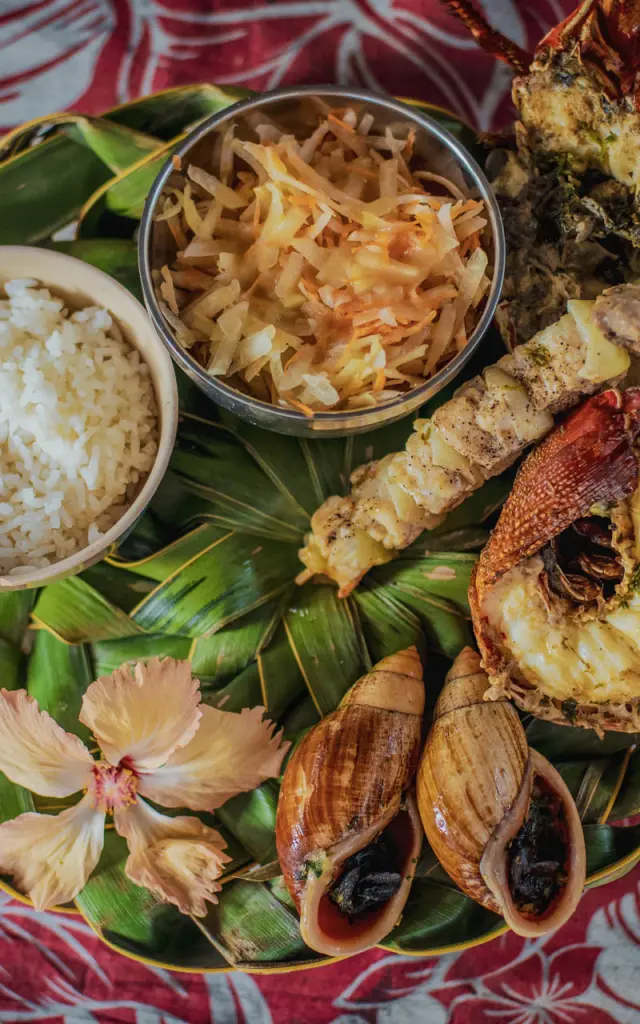 Déguster un repas calédonien : bulimes, langouste et poisson grillées accompagnés de riz et d'une salade.