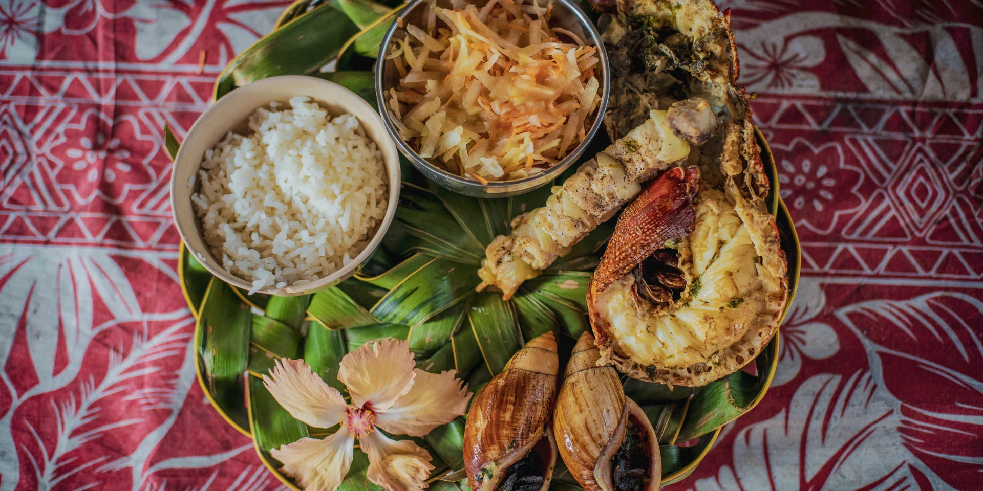 Déguster un repas calédonien : bulimes, langouste et poisson grillées accompagnés de riz et d'une salade.