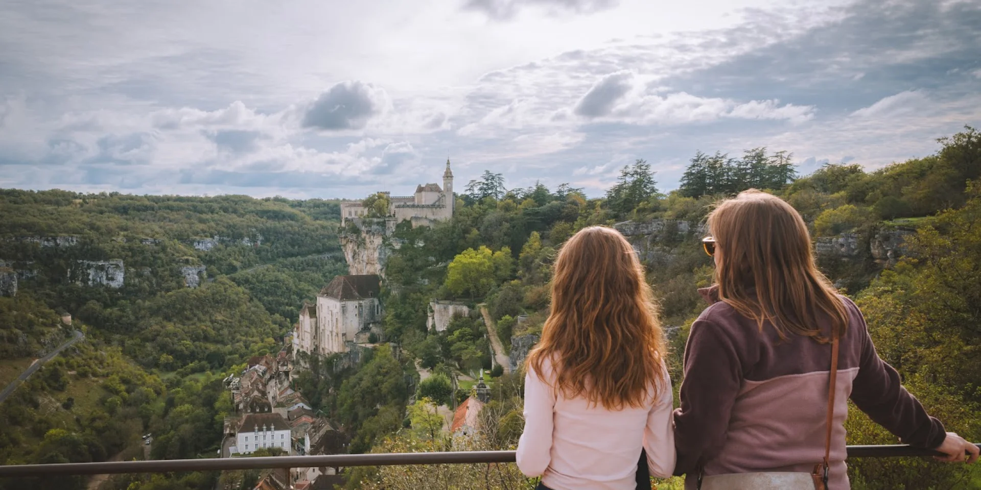 Une mère et sa fille se tiennent sur le belvédère du photographe de Rocamadour et observent la cité médiévale accrochée à la falaise.