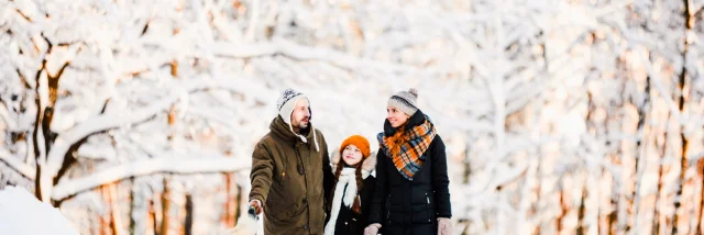 Wide angle portrait of happy family walking dog in beautiful winter forest, copy space