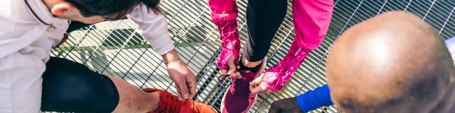 Multiethnic group of runners getting ready for a workout session - Athletes tying shoelaces and resting after a run outdoors