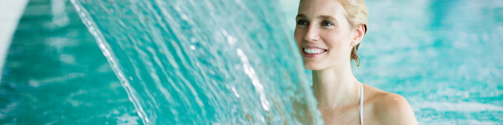 Woman enjoying hydrotherapy and water stream in spa pool