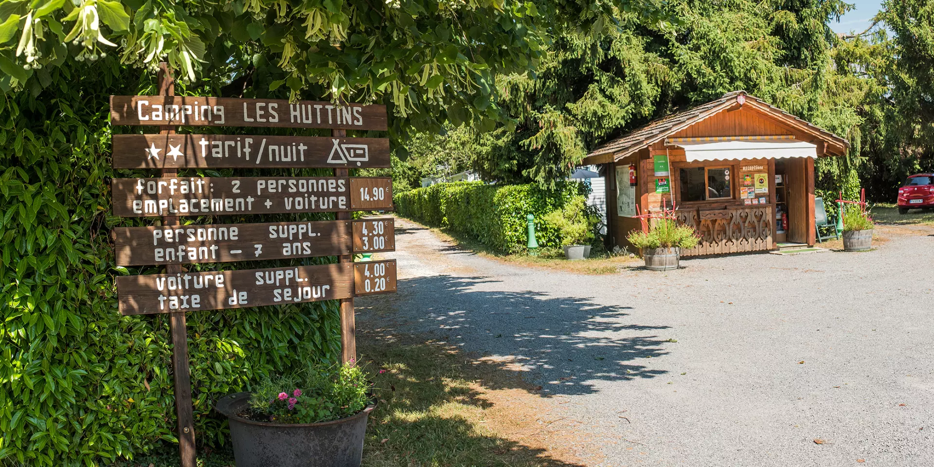 Camping Des Huttins Amphion, panels under the trees and small wooden cottage