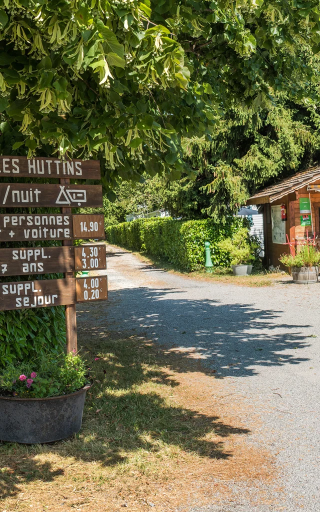 Camping Des Huttins Amphion, panels under the trees and small wooden cottage