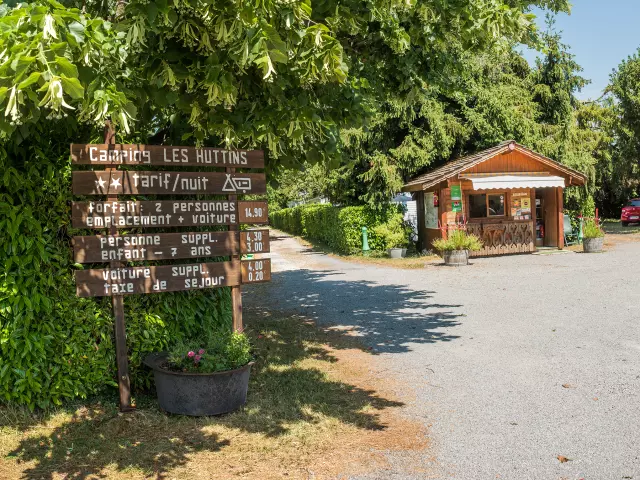 Camping Des Huttins Amphion, panneaux sous les arbres et petite maisonnette en bois
