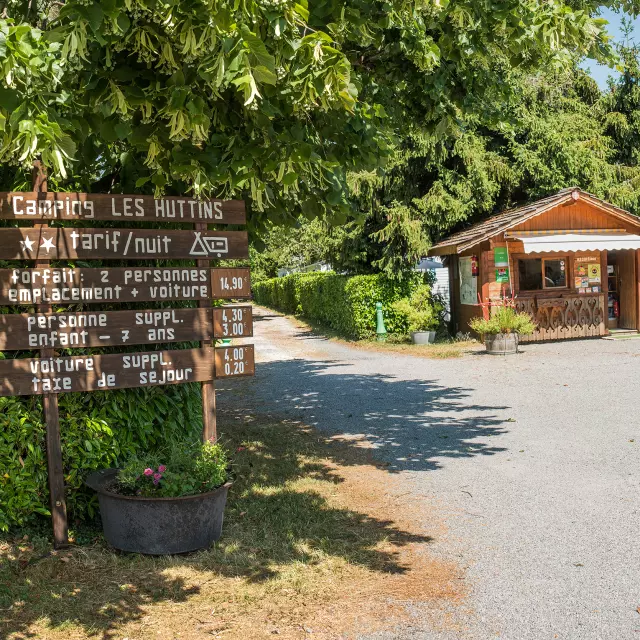 Camping Des Huttins Amphion, panneaux sous les arbres et petite maisonnette en bois