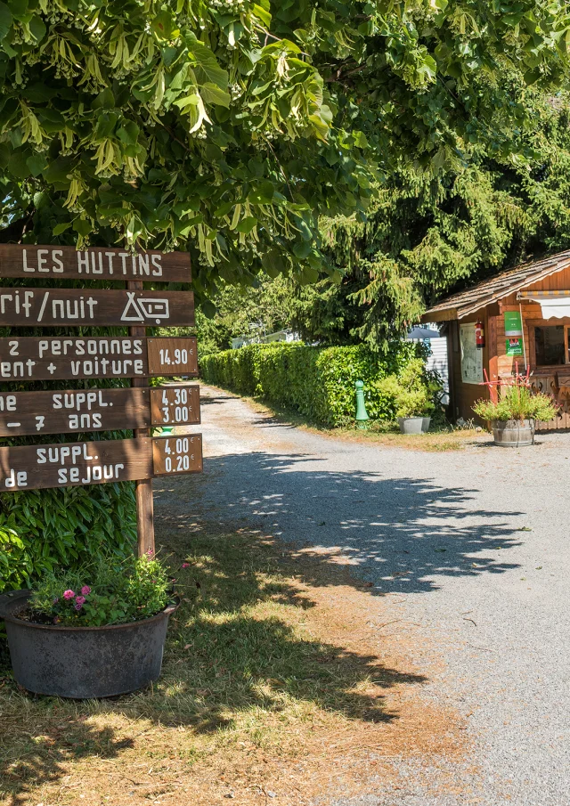 Camping Des Huttins Amphion, panels under the trees and small wooden cottage