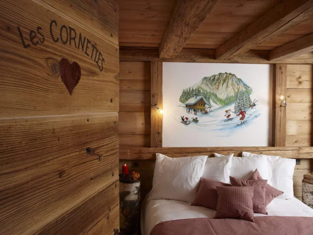 Chambre en bois, lit sur la droite avec un tableau de skieur au dessus