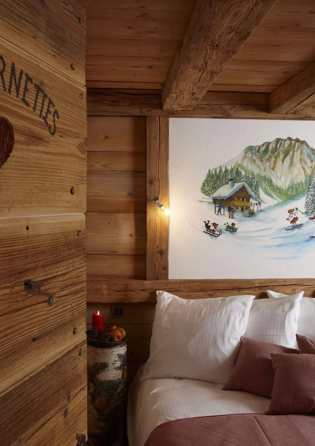 Chambre en bois, lit sur la droite avec un tableau de skieur au dessus