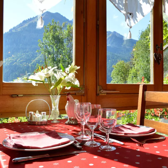 Table ready to serve a meal, red tablecloth, flowers in a vase and mountain view