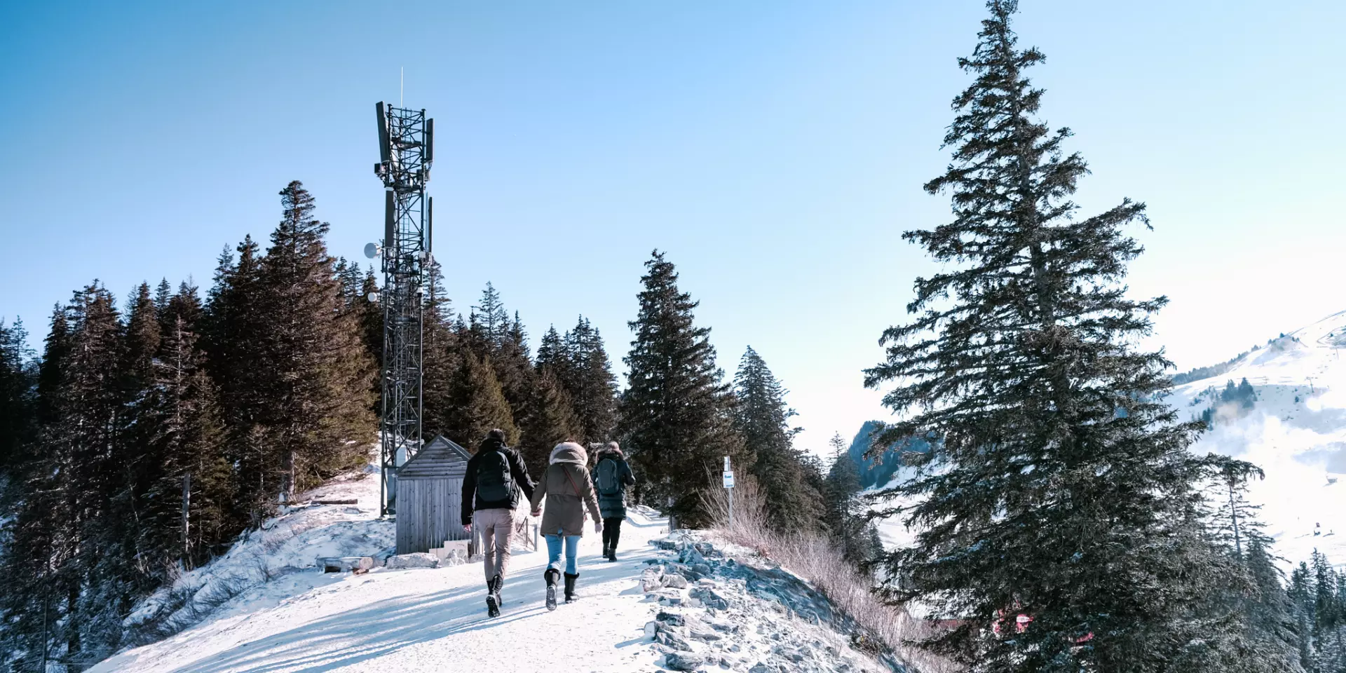 Snowy trail in Thollon Les Memises. A couple stroll hand-in-hand along a snow-covered ridge.