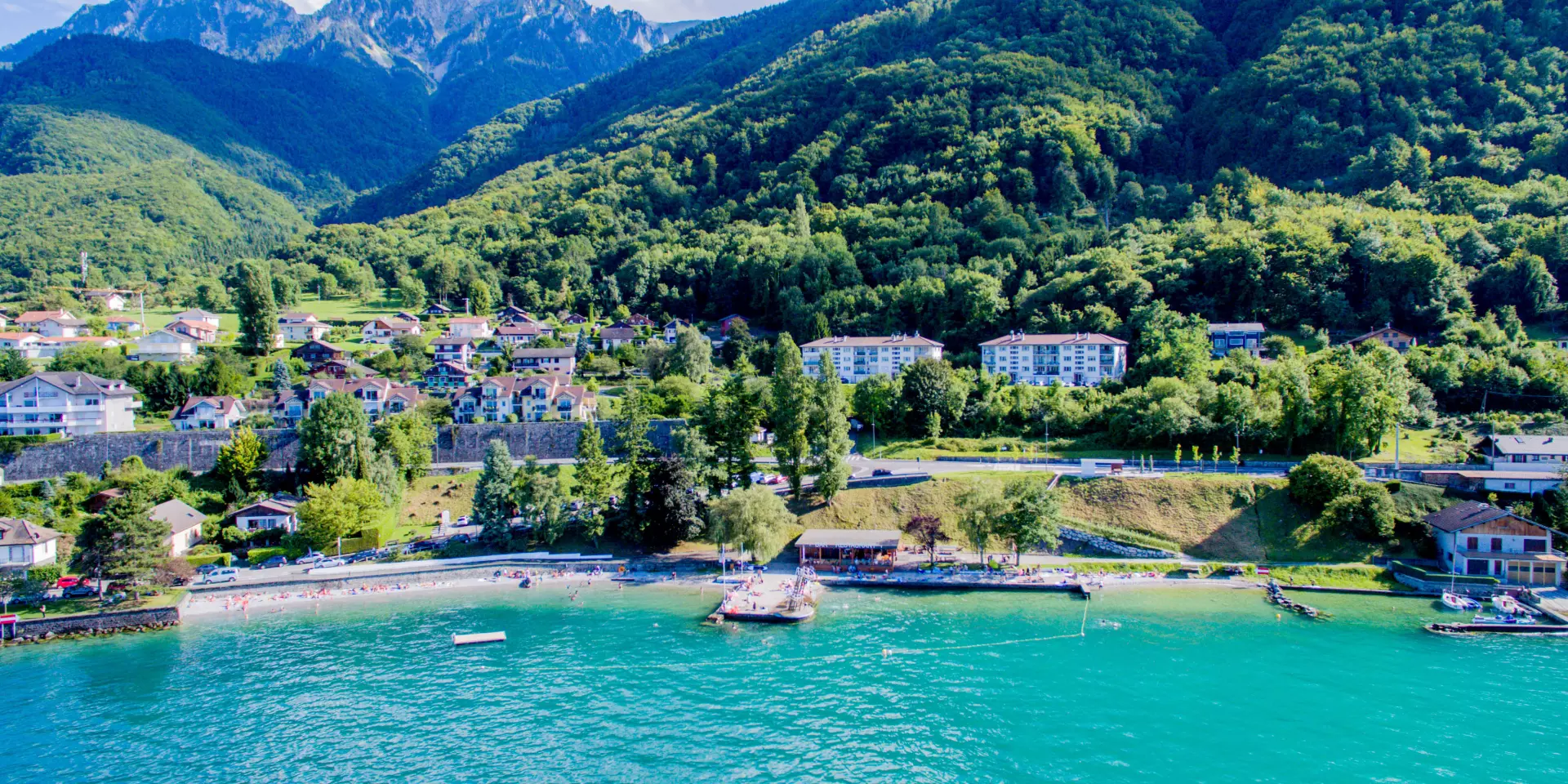 Drone view from the lake. The water is blue and you can see the mountain in the background with the port.
