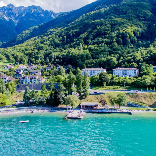 Drone view from the lake. The water is blue and you can see the mountain in the background with the port.