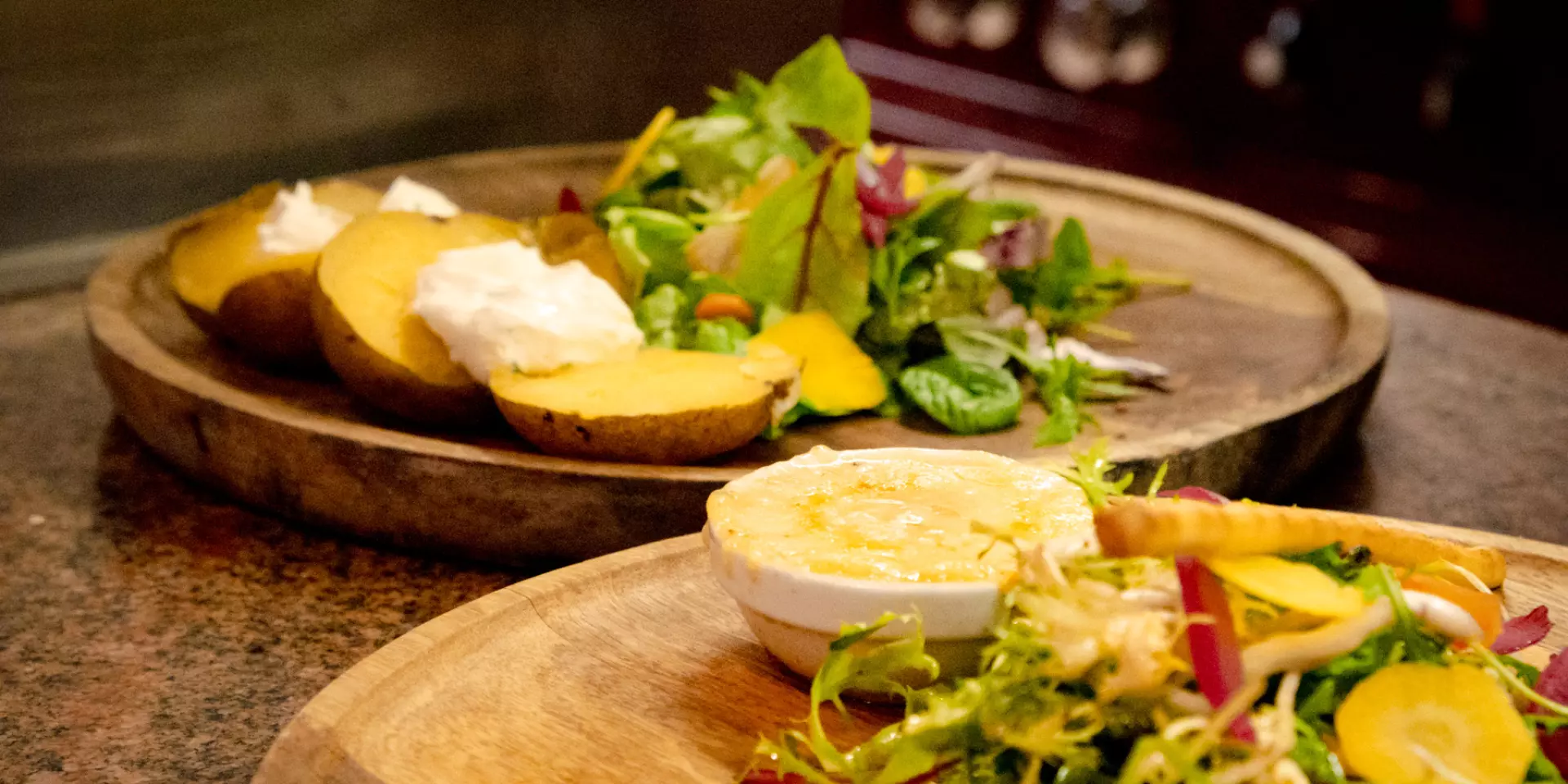 A cheese and salad dish on a wooden tray