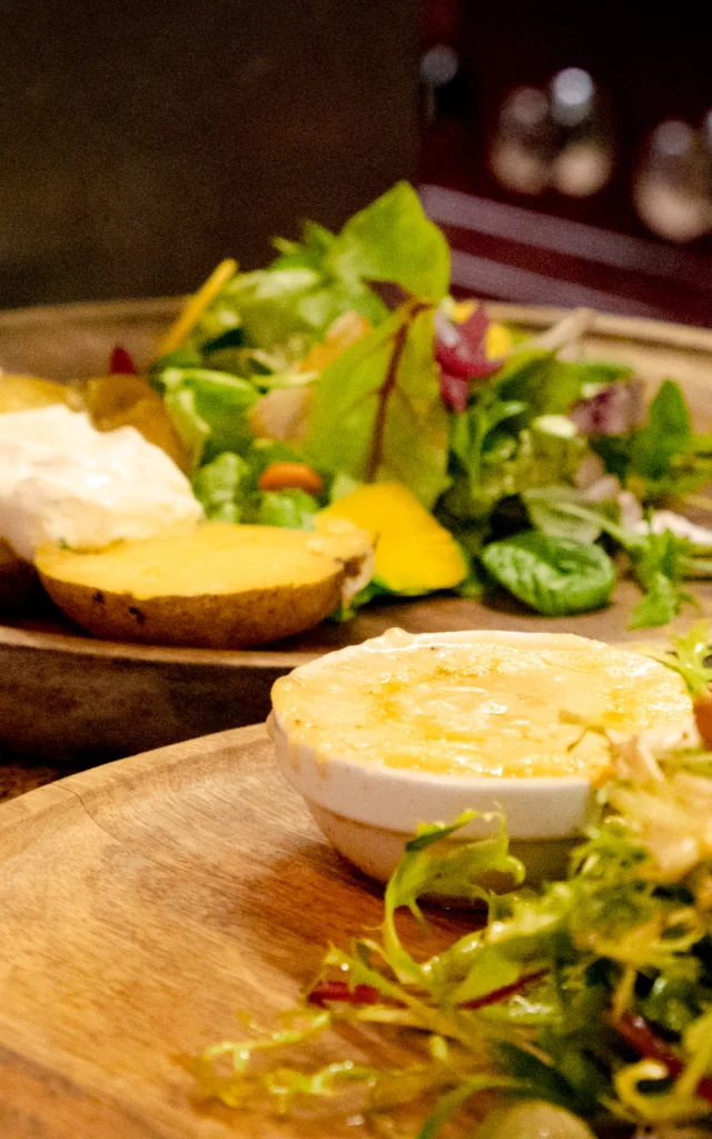 A cheese and salad dish on a wooden tray