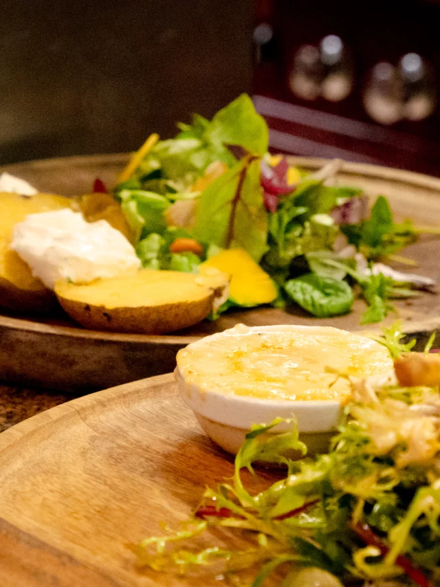 A cheese and salad dish on a wooden tray
