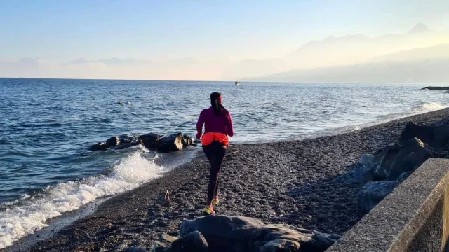 Une femme cours sur une plage de galets au bord du lac