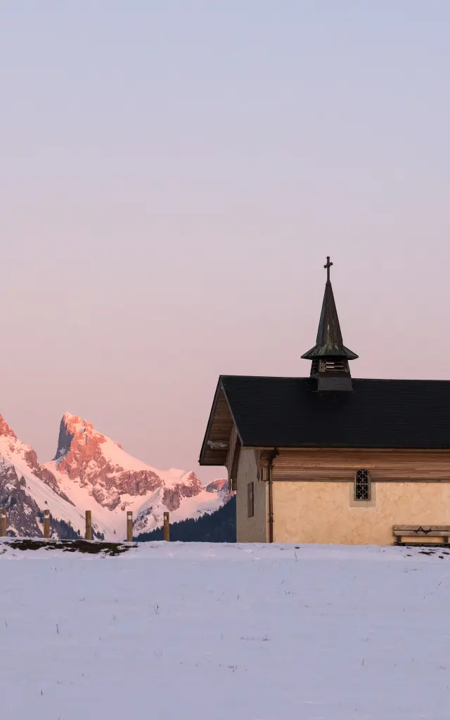 La chapelle de Champeillant en hiver, au coucher de soleil avec la Dent d'Oche enneigée en arrière plan.