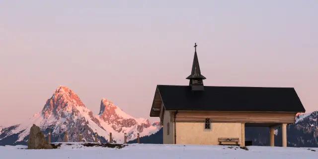 La chapelle de Champeillant en hiver, au coucher de soleil avec la Dent d'Oche enneigée en arrière plan.