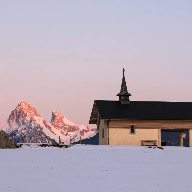 La chapelle de Champeillant en hiver, au coucher de soleil avec la Dent d'Oche enneigée en arrière plan.