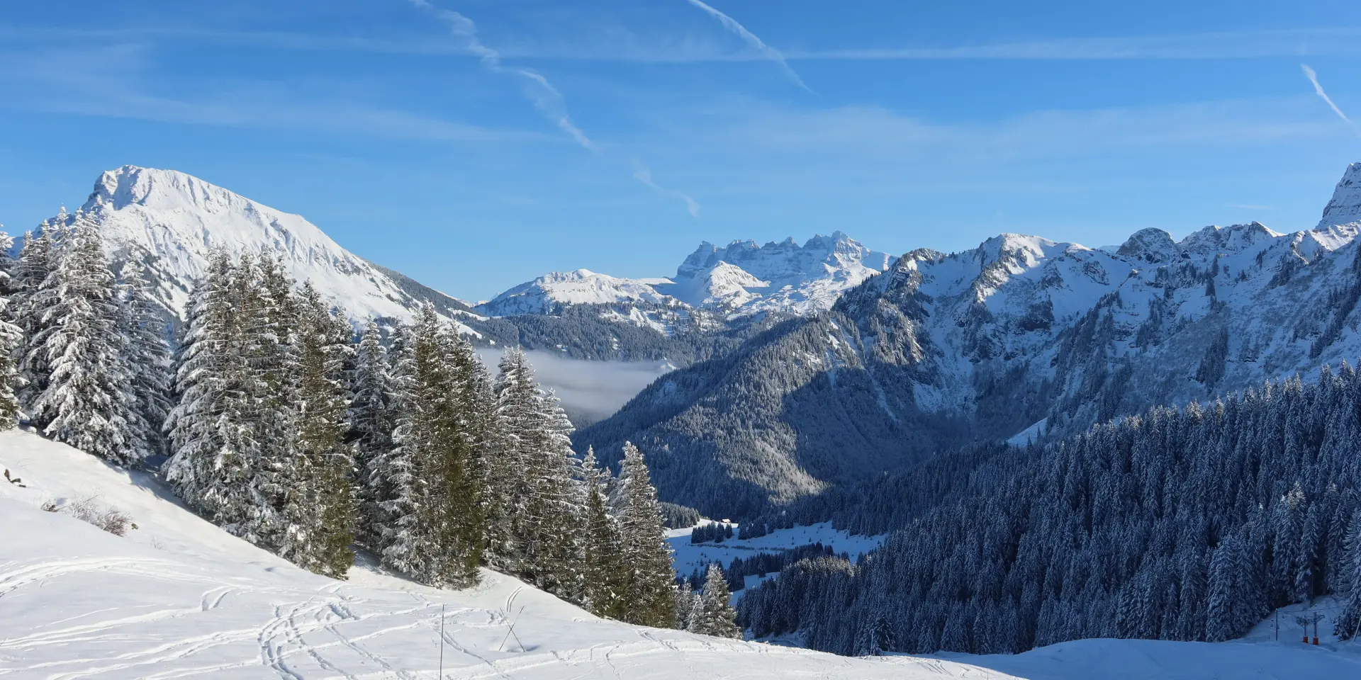 Domaine skiable d'Abondance avec vue sur les montagnes enneigées alentours, depuis les pistes, sous un grand ciel bleu