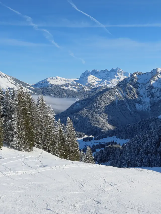 Domaine skiable d'Abondance avec vue sur les montagnes enneigées alentours, depuis les pistes, sous un grand ciel bleu