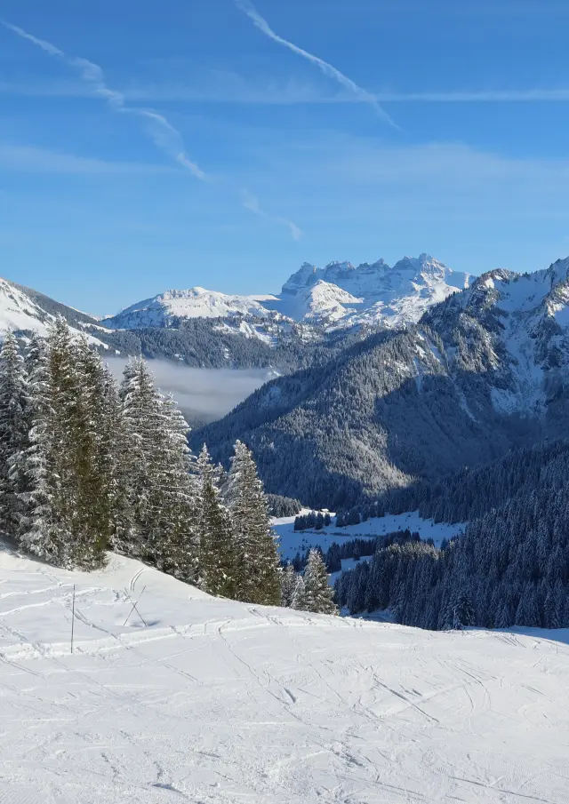 Domaine skiable d'Abondance avec vue sur les montagnes enneigées alentours, depuis les pistes, sous un grand ciel bleu