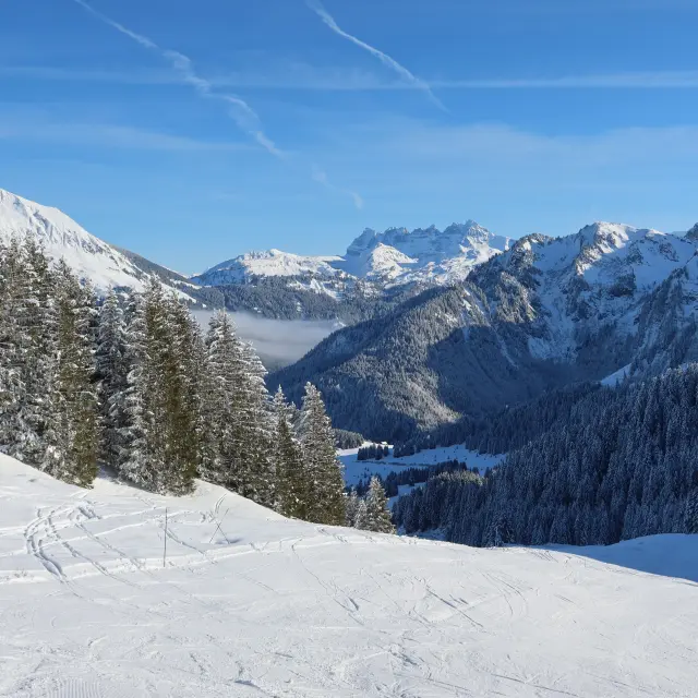 Domaine skiable d'Abondance avec vue sur les montagnes enneigées alentours, depuis les pistes, sous un grand ciel bleu