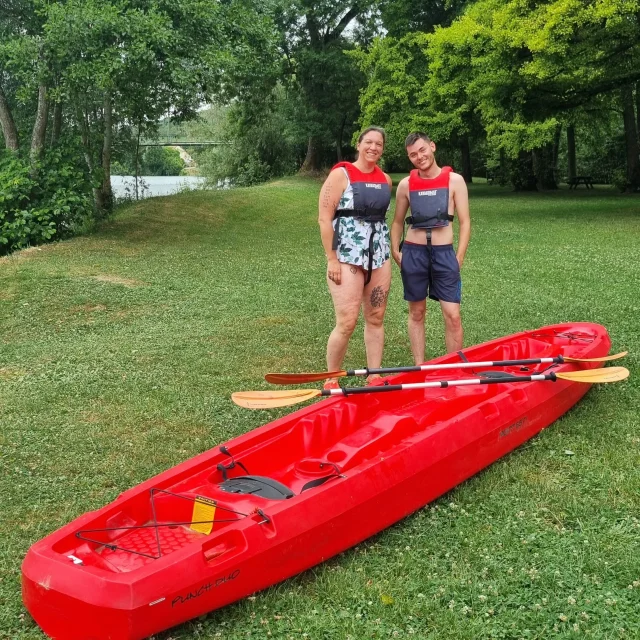 Deux personnes à côté d'un canoë rouge sur la rivière Marne à Jaulgonne.